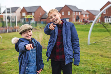 Young boys laughing and pointing at camera - Two boys having fun and mocking the viewer pointing with fingers at camera - Childhood theme with cute modelsの写真素材