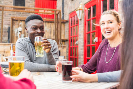Happy multiracial friends enjoying drink together - Friendship lifestyle concept with young people spending time together at pub in London - Black, asian and caucasian peopleの写真素材