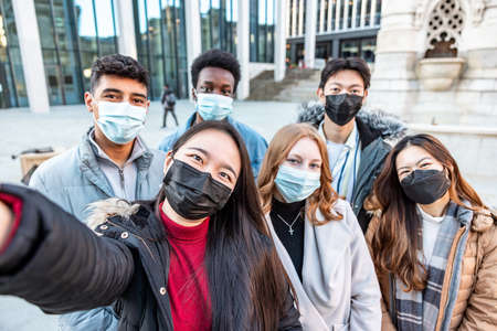 Authentic shot of happy group of multiracial friends millennials and generation z people taking a selfie together wearing face mask - Friendship and lifestyle conceptsの写真素材