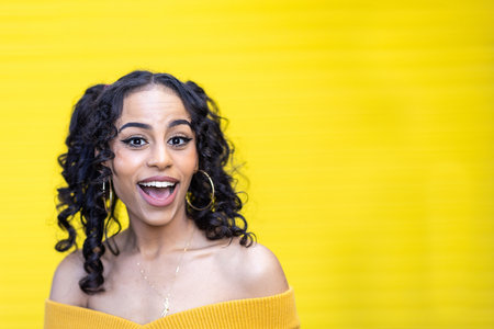 Happy black woman portrait with yellow background smiling at camera - Beautiful multirace young...