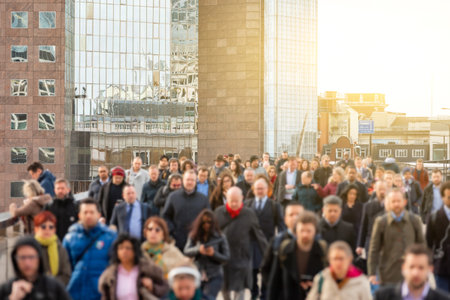Crowd of unrecognisable people walking and crossing London Bridge in the city at rush hour - Commuters lifestyle in a big city in Europe - Focus on the buildingの写真素材