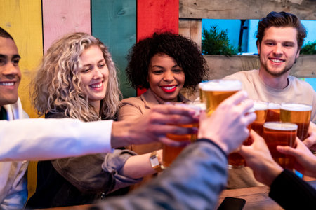 Friends drinking and toasting with beer at pub brewery - Beautiful smiling multiracial people cheering with pint of beer - Lifestyle and drink concepts in Londonの写真素材