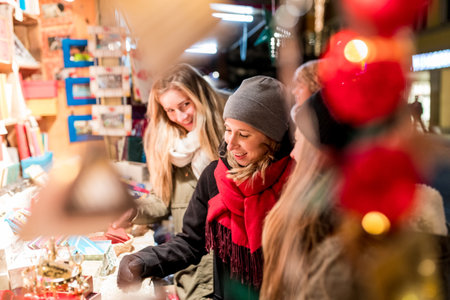 Happy young women shopping at Christmas market in Innsbruck - Smiling girls enjoying time out together and buying warm clothing in Austria - Lifestyle and culture conceptsの写真素材