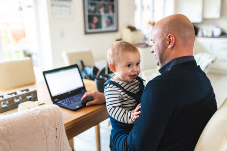 Happy baby boy with hid father working from home - Man and son together in the living room -...