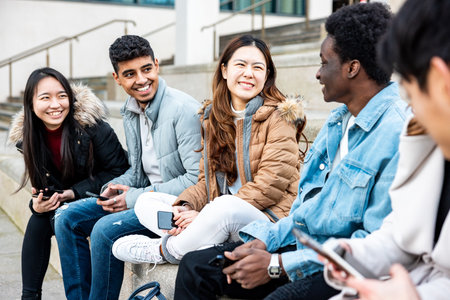 Authentic shot of happy group of multiracial friends millennials and generation z people in the city using mobile phones and laughing together - Friendship and lifestyle conceptsの写真素材