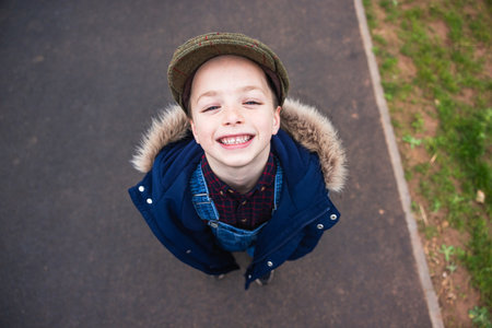 Joyful boy portrait from above - Young boy looking up at camera and smiling with a funny grimace - Childhood and carefreeの写真素材