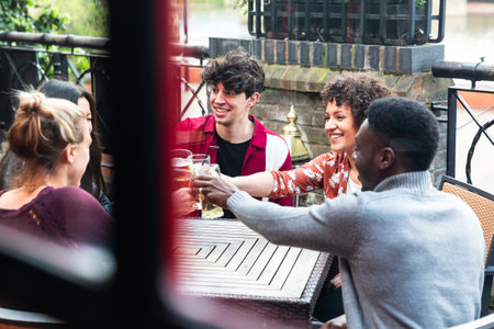 Happy multiracial friends enjoying drink together - Friendship lifestyle concept with young people spending time together at pub in London - Black, asian and caucasian peopleの写真素材
