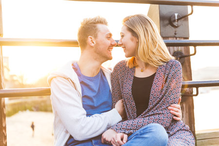 Happy man and woman laughing and cuddling outdoors at dusk - Joyful caucasian couple enjoying sunset together on a pier in London along Thames riverの写真素材