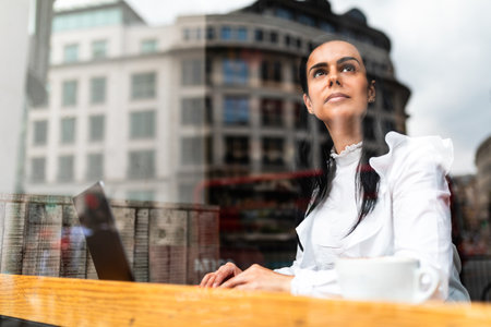 Pensive business woman working from a cafe in the city - Woman at the table with computer and coffee, working from remote during a break - Authentic people lifestyle in Londonの写真素材