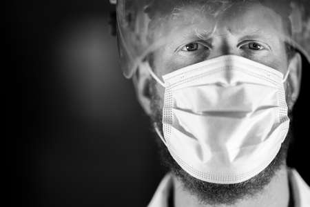 doctor and health care worker, putting on a mask and face shield, while wearing a lab coat and glovesの写真素材