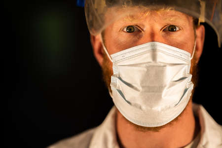 doctor and health care worker, putting on a mask and face shield, while wearing a lab coat and glovesの写真素材