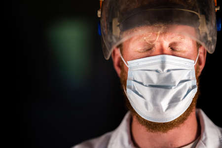 doctor and health care worker, putting on a mask and face shield, while wearing a lab coat and gloves in Australia.の写真素材