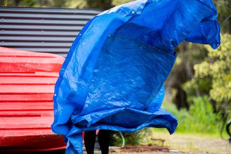 girl folding up a tent and blue tarp hikingの写真素材