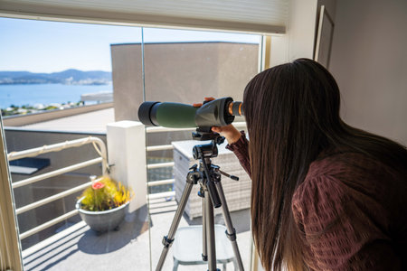 Girl using binoculars on a balcony in a city next to the sea, seaside town in hobart AUSTRALIA bird watchingの写真素材