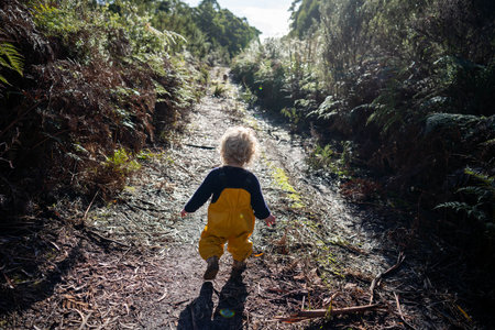 toddler exploring in yellow overalls in the forest in winter