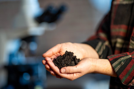Female farmer holding soil, doing soil tests in her home laboratory. Looking at soil life and health in australiaの写真素材