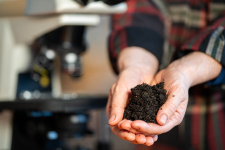 Female farmer holding soil, doing soil tests in her home laboratory. Looking at soil life and health in australiaの写真素材