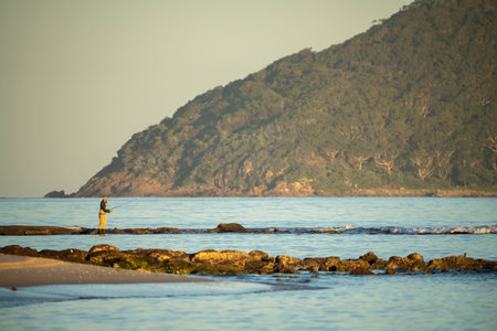 beach fishing in the ocean waves at dusk on a holiday in summerの写真素材