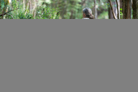 Mother with baby in a carrier on her chest on a hike, taking a bush walk in Summer in a national...