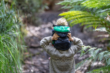 mother giving child a piggyback ride in the forestの写真素材