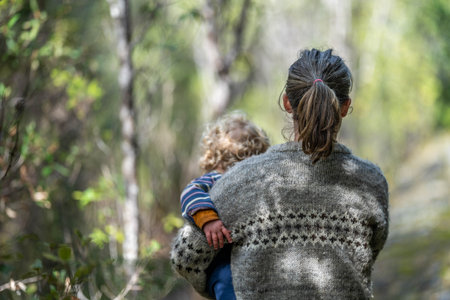 Mother with baby in a carrier on her chest on a hike, taking a bush walk in Summer in a national parkの写真素材