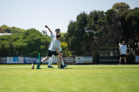 a local cricket match being played on a green cricket oval in summer in australiaの写真素材