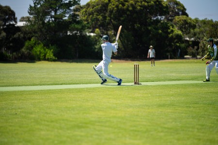 a local cricket match being played on a green cricket oval in summer in australia