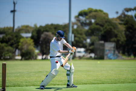a local cricket match being played on a green cricket oval in summer in australia
