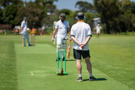 a local cricket match being played on a green cricket oval in summer in australia. australian cricketer batting and bowling in a game in summerの写真素材