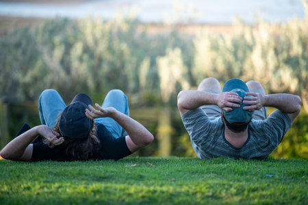 friends watching the sunset over the beach and ocean eating a takeway dinnerの写真素材