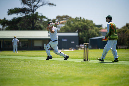 a local cricket match being played on a green cricket oval in summer in australia