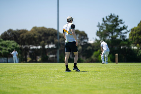 a local cricket match being played on a green cricket oval in summer in australia. australian...