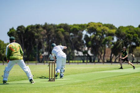a local cricket match being played on a green cricket oval in summer in australia. australian...