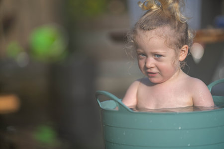 Little girl bathes in a bathtub on a hot summer day