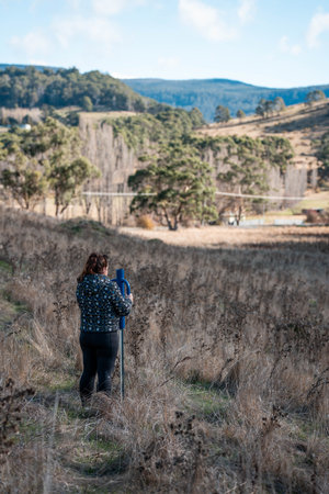 female farmer driving steel posts with a post driver on a farm putting up a steel post fence with...