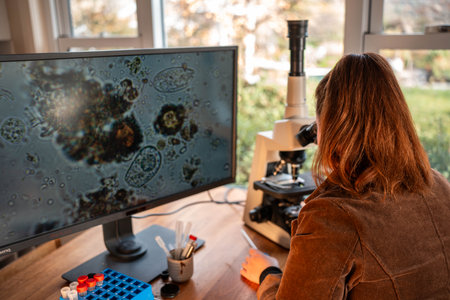 farmer collecting soil samples in a test tube in a field. Agronomist checking soil carbon and plant health on a farm with a microscope soil test in australiaの写真素材