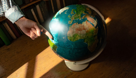 indicating with your finger some place on earth on a globeの素材