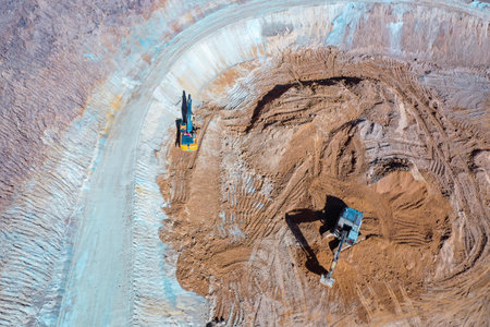 Open pit mine in full operation, with machinery extracting minerals.の写真素材
