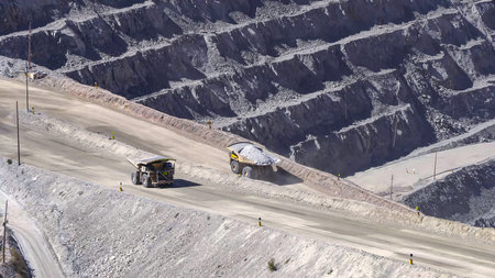 Giant mining trucks transporting minerals in an open pit mineの写真素材