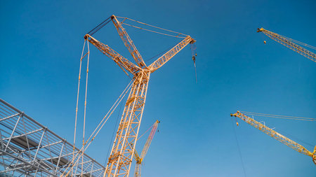 Crane towers in the process of hoisting metal structures for stadium constructionの写真素材