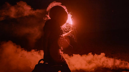 Halloween human pumpkin or Jack o lantern costume on a dark night with lots of smoke, a chainsaw,...