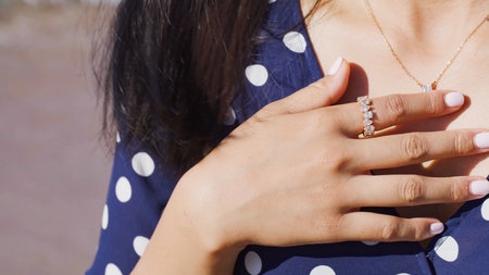 Woman's hand showing gold engagement ring encrusted with precious stones and diamonds