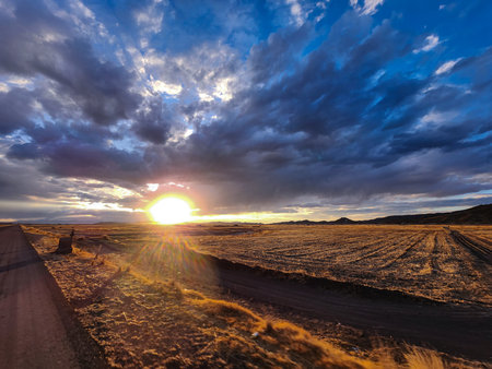 Sunset view over high Andean grasslands with many clouds and roadsの写真素材
