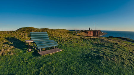 View of a bench installed in green gardens facing the sea to admire the sunsetの写真素材