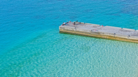 Aerial view of a pier on a beach with crystal clear waterの写真素材