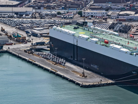 Aerial view of a port terminal next to a huge ro-ro ship in the process of unloading automobiles.
