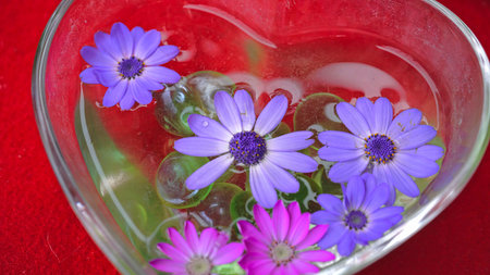 View of a heart-shaped glass vase with many flowers insideの写真素材