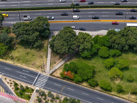 Aerial view of a highway in a city with a road interchange next to many gardens.