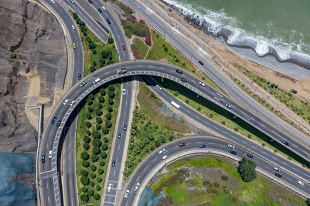 Aerial view of a highway in a city with a road interchange next to many gardens.