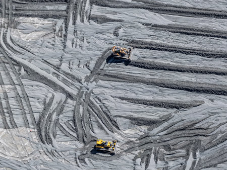 Panoramic view of a mining tailings dam with bulldozers removing sedimented material